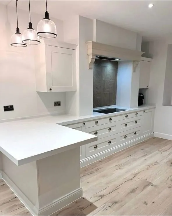White shaker kitchen with glass pendant lights and range hood